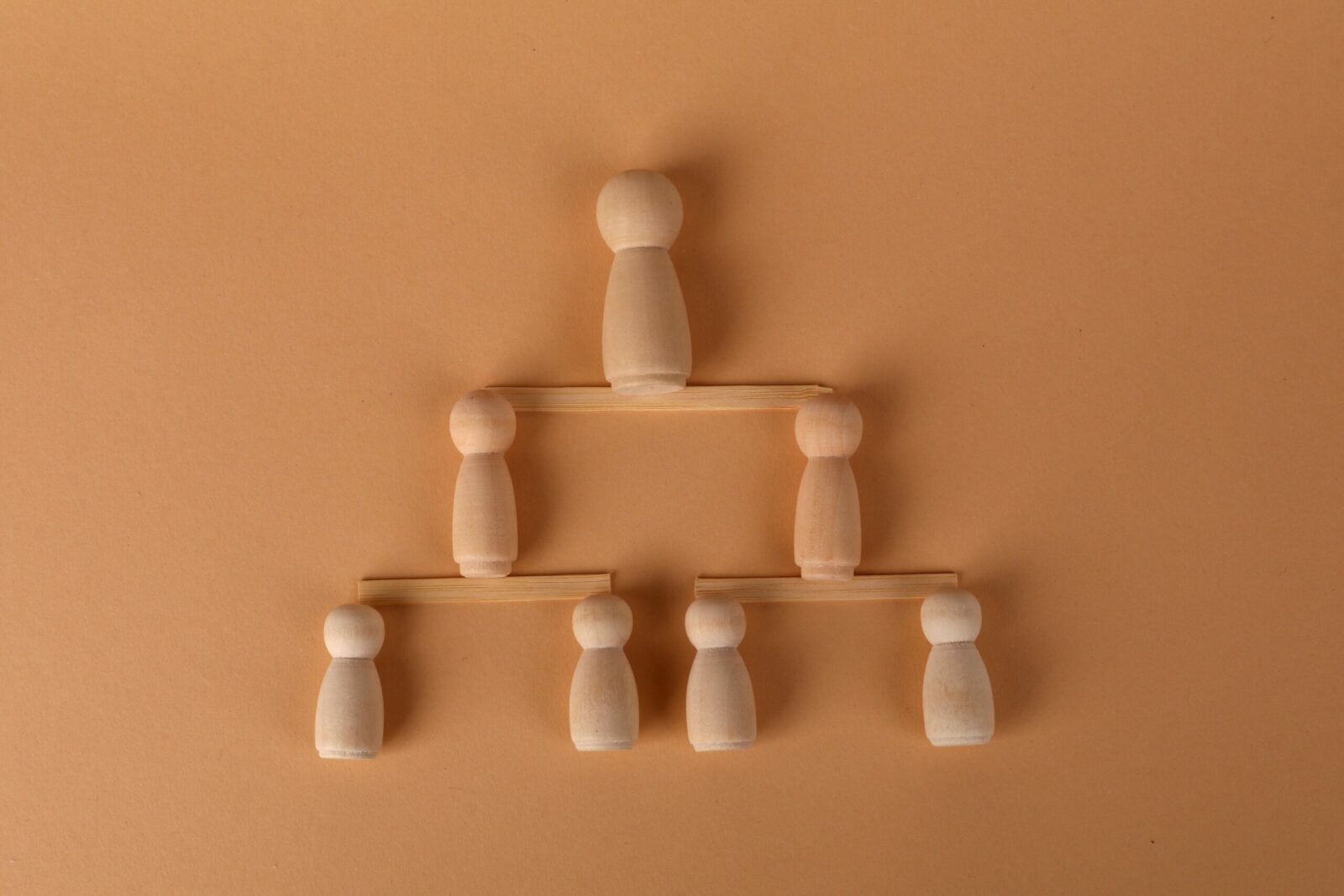 Wooden peg dolls arranged in a pyramid, symbolizing leadership and teamwork.